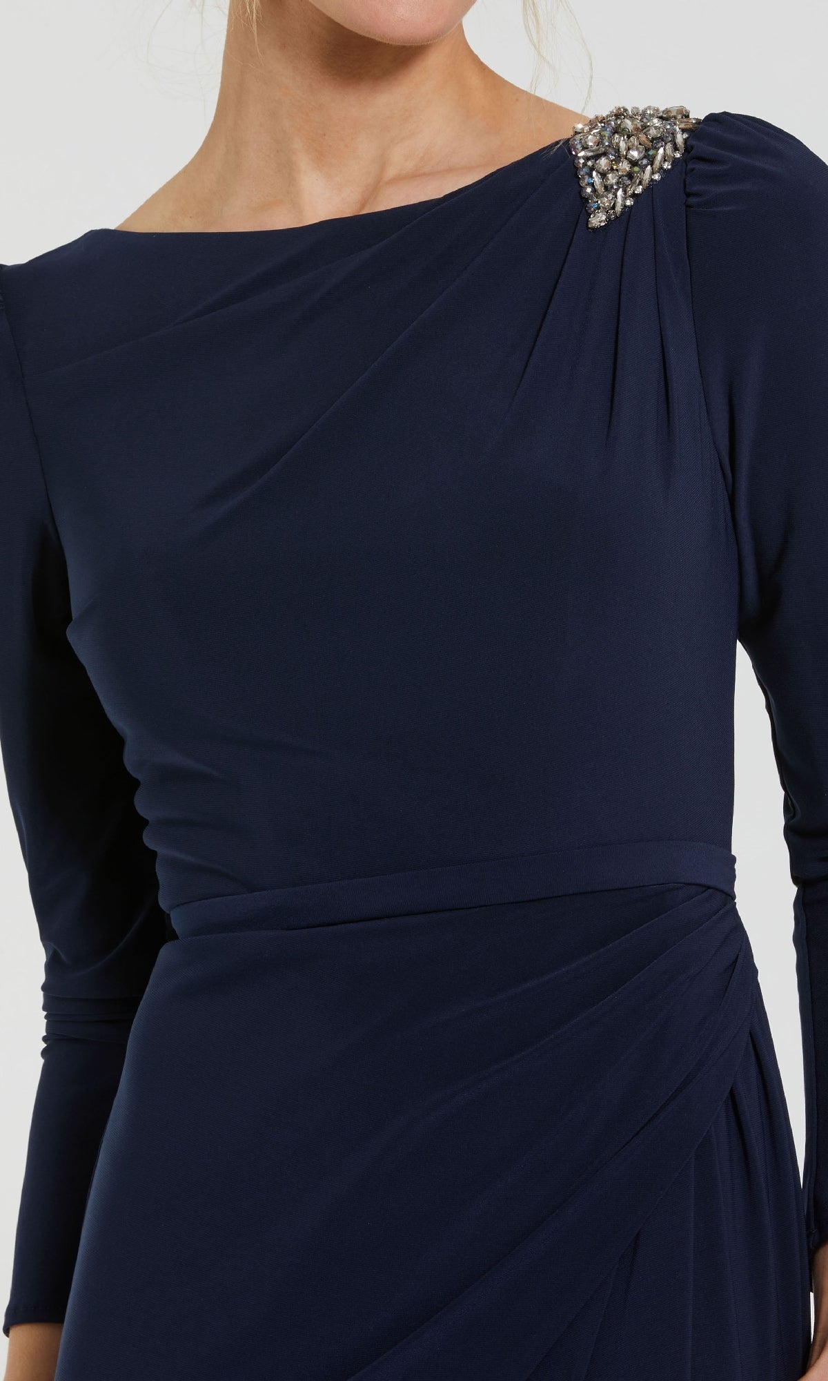 A woman wears the Long Formal Dress 55695 by Mac Duggal—a dark blue, high-neck formal gown with long sleeves, pleated details, and decorative beaded shoulder embellishment.